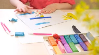 Bir kız plastikten heykel yapar, bir çocuk kartondan plastik çizimler yapar.