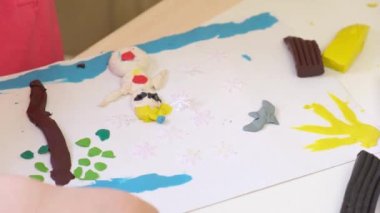 Bir kız plastikten heykel yapar, bir çocuk kartondan plastik çizimler yapar.