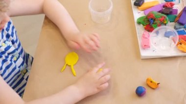 Bir kız plastikten heykel yapar, bir çocuk kartondan plastik çizimler yapar.