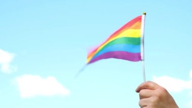 el, lgbt topluluğunun bayrak sembolünü taşıyor, gökyüzü arka planında bulutlu gurur kavramı