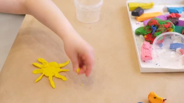 En flicka skulpterar från plasticine, ett barn gör en teckning från plasticine på papp — Stockvideo