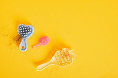 Sarı arka planda birkaç oyuncak bebek saçı, saç dökülmesi tarakları, saç dökülmesi konsepti