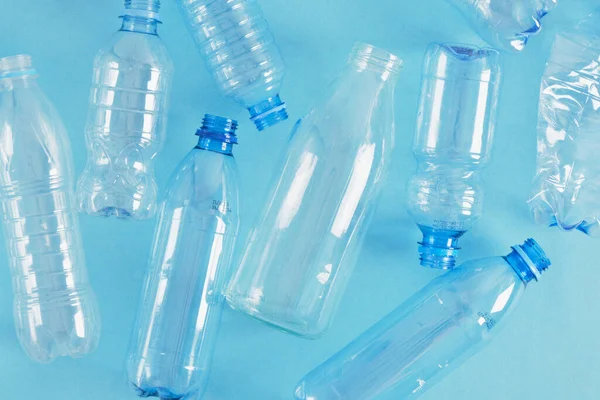 Una Botella Vidrio Entre Varias Botellas Plástico Sobre Fondo Azul — Foto de Stock