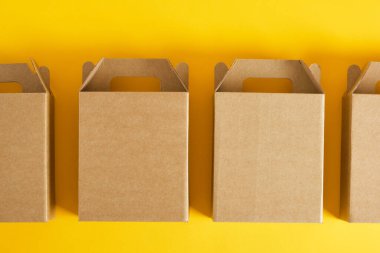 Sarı arka planda birkaç karton kutu, hediye ya da ürün teslimatı için logo olmadan kutular, tasarımınız için boş paket