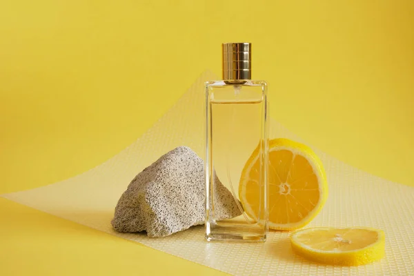 citrus scent, perfume with lemon scent concept, concrete block fragment, lemon slice and bottle of perfume on yellow background