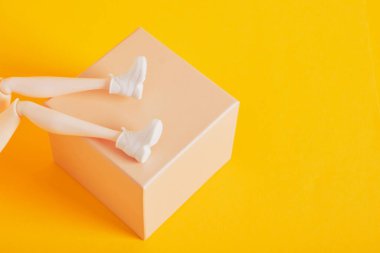 Beyaz spor ayakkabılı oyuncak ayaklar hediye kutusunda sarı arka plan fotokopi alanı