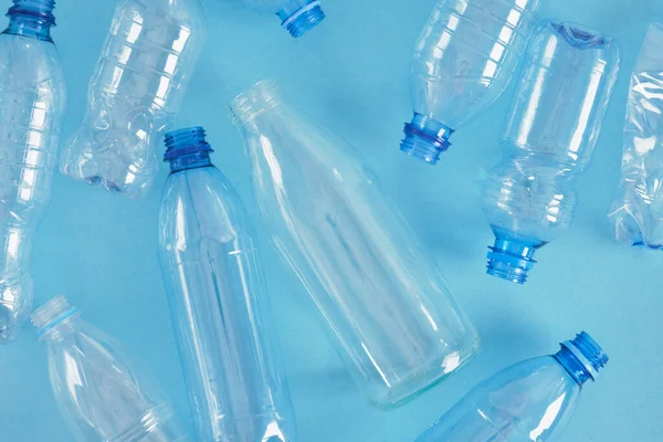 Una Botella Vidrio Entre Varias Botellas Plástico Sobre Fondo Azul — Foto de Stock