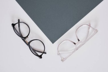 Gri arkaplanda iki modaya uygun gözlük, geometri arka plan fotokopi alanı, üst görünüm, arka plan optik kavramında koyu yeşil kağıt