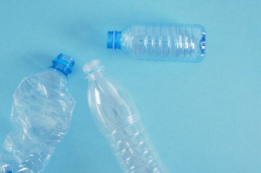 Mavi arka planda birkaç plastik şişe var. Sıfır atık, doğanın kirliliği, çevre dostu kavram. Boşluk üst görünümünü kopyala