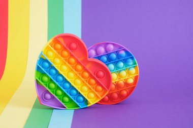 Kalp ve çember şeklinde renkli anti-stres oyuncağı. Duyusal oyuncak. Gökkuşağı arkaplanına yerleştir.