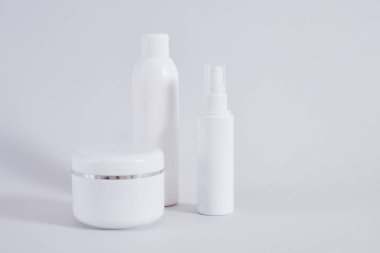 Farklı kozmetik şişelerinin kompozisyonu gri arka plan, krema kavanozu, yağ ya da jöle şişeleri ve parfüm için Sparay şişesi.