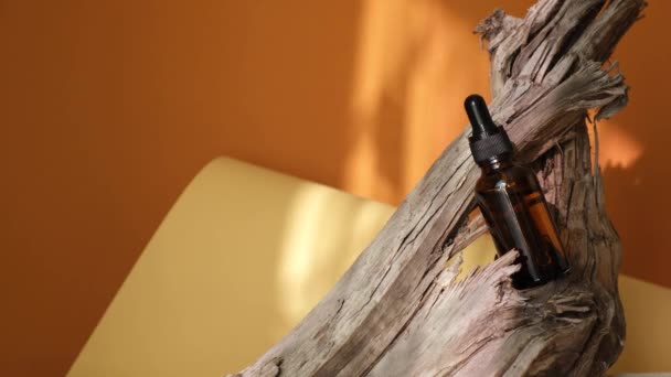 Garrafa de vidro âmbar de perfume em um pódio de madeira à deriva, no fundo marrom, fundo de sombra natural — Vídeo de Stock