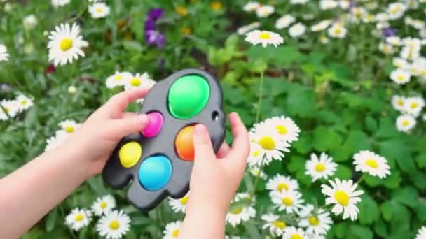 Kind spielt mit Antistress-sensorischen Spielzeug Fidget Push Pop-it oder einfach Grübchen außerhalb — Stockvideo