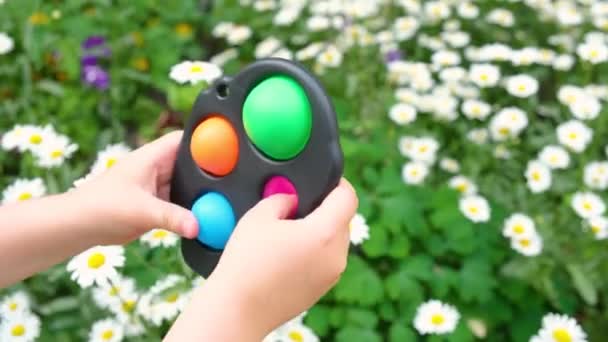 Criança brincando com antistress brinquedo sensorial fidget empurrá-lo pop-lo ou covinha simples fora — Vídeo de Stock