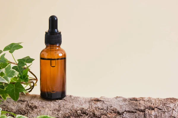 Kehribar cam şişe ve yüz serumu ya da bej arka planda ağaç kabuğu yağı. Doğal kozmetik konsepti