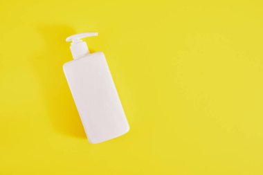 Bir şişe sıvı sabun, sarı zemin üzerinde şeker kutusu olan beyaz plastik bir şişe. Boşluğu kopyala, hijyen kavramı.