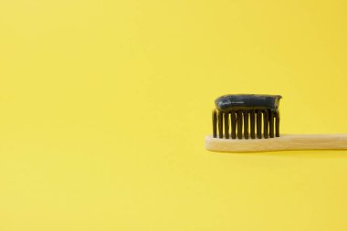 Kömür sarısı arkaplan ile siyah kömür diş macunu ile bambu diş fırçası