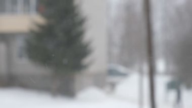 Şehre kar yağışı, pencereden manzara. Kar yığınları. Karlı ağaçlar, arabalar, binalar ve yol seçici odak noktası