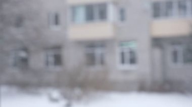 Şehre kar yağışı, pencereden manzara. Kar yığınları. Karlı ağaçlar, arabalar, binalar ve yol seçici odak noktası