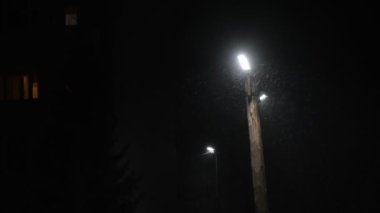 Sokak lambası ve gece karı, kar taneleri lambanın ışığında, karanlık gece