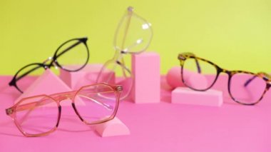 Pembe ang sarı zemin üzerinde çoklu gözlük, geometrik tribünler, moda gözlük çerçeveleri