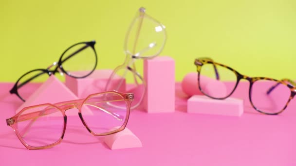 Multiple eyeglasses on a pink ang yellow background, geometric stands, trendy eyeglass frames — Stock Video