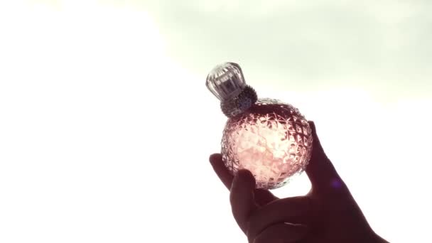 Pembe kristal şişe spreyi. Elinde parfüm var. Pencere ve güneş ışığı. — Stok video