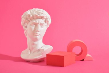 Beyaz dekoratif heykel büstü ve pembe arka plan geometrik şekilli birkaç pembe geometrik bardak altlığı. Sergi podyumu, ürün sunumu platformu