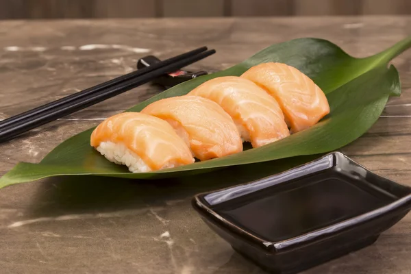 Sushi syake set on green leaf with soy sauce and sticks — Stock Photo, Image
