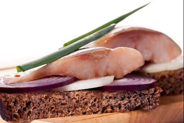 The pieces of salted herring on rye bread with slices of red onion — Stock Photo, Image