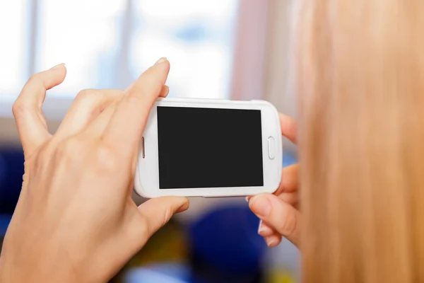 Bir cep telefonu tutan ve bir video ya da fotoğraf çekici genç kadın
