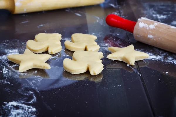 Plätzchen zubereiten, verschiedene Formen von rohem Teig auf dem Tisch — Stockfoto