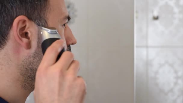 Людина обрізає бороду на дзеркалі у ванній — стокове відео