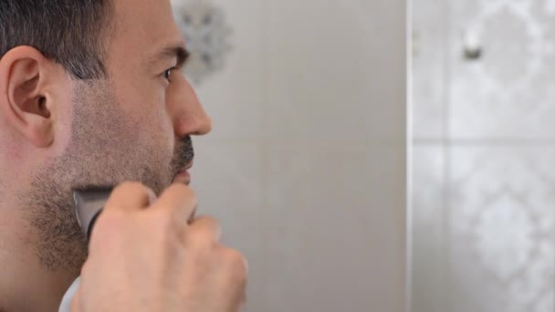 Hombre recortando la barba en el espejo en el baño — Vídeo de stock