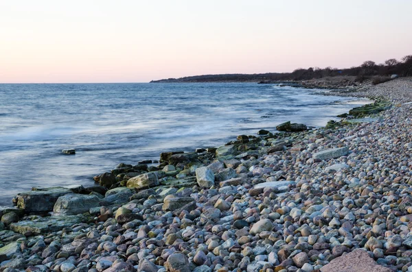 Kvällen ljus genom en stenig kust — Stockfoto