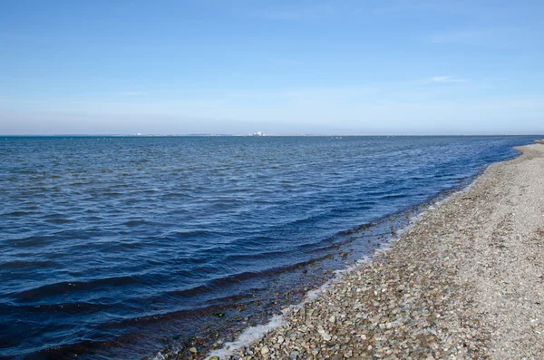 Береговая линия с голубой водой и галькой — стоковое фото