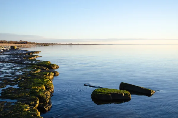 Plochý kámen pobřeží s klidnou vodou — Stock fotografie