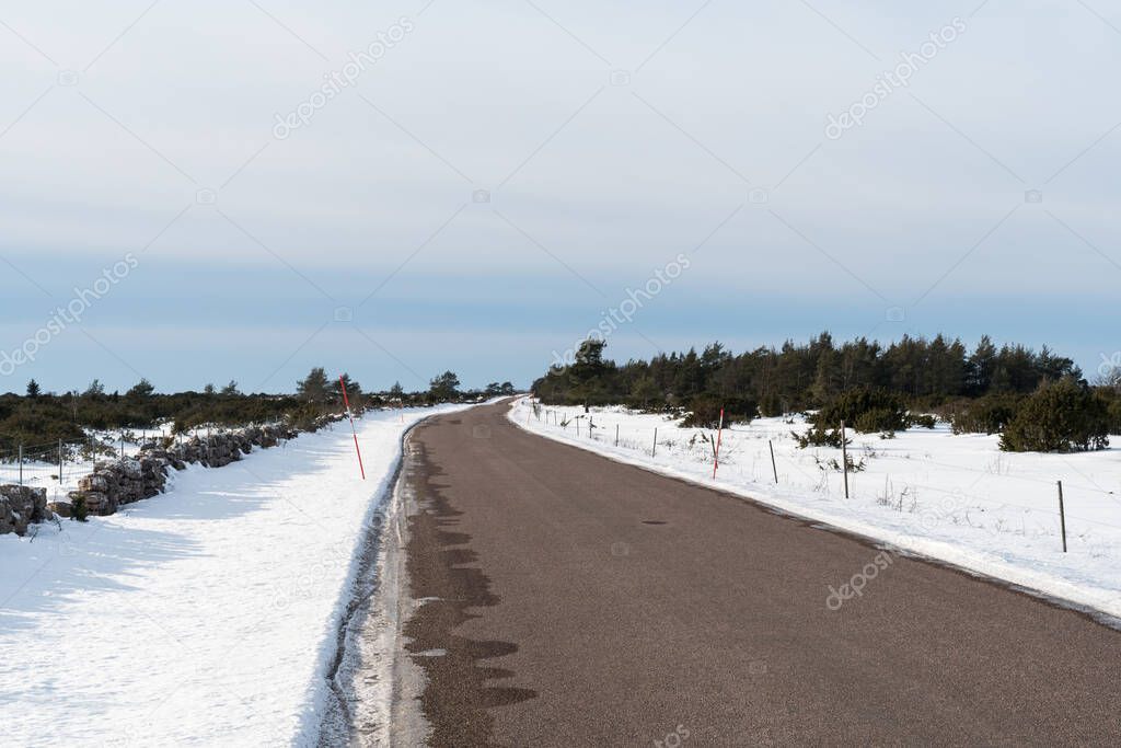 Winding country road with snow stakes by roadside in the Great Alvar plain on the island Oland in Sweden