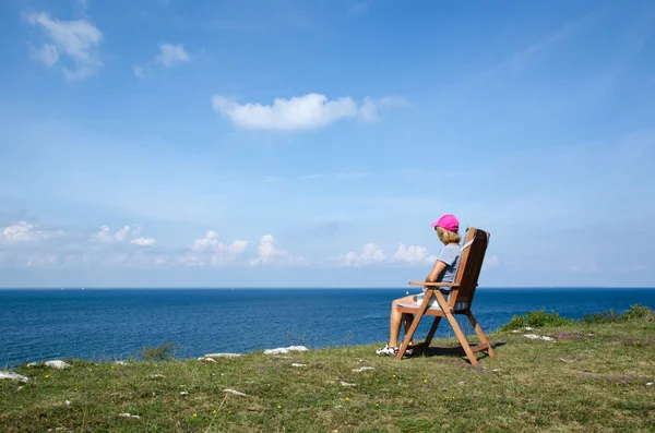 Frau beobachtet Blick auf Küste von einem Stuhl aus — Stockfoto