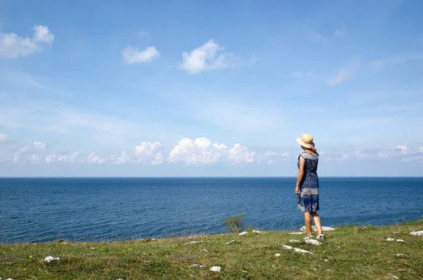 Woman standing in summer by seaside wathing the horizon — Stock Photo, Image