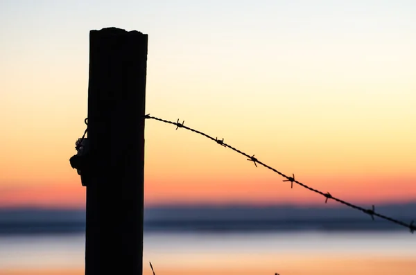 Silhouette of barb wire at a post — Stock Photo, Image