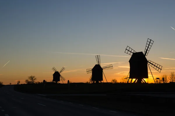 Silhuetas de moinhos de vento à beira da estrada ao pôr do sol — Fotografia de Stock