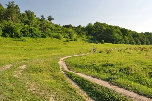 Girl rides a bike path near a forest — Stock Photo, Image