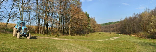 Tractor standing near the trees — Stock Photo, Image