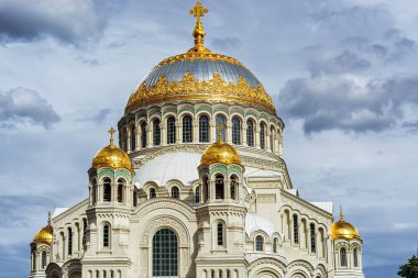 Donanma Nikolsky Katedrali 'nin kubbeleri, Kronstadt şehrinde altın kaplama ve haçlarla dolu bir yaz gününde gri bulutlu bir gökyüzünün arka planına karşı..