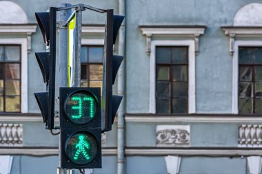 Yayalar için trafik ışığı, kronometre ekranlı yeşil renk. Trafik ışıklarına odaklan, arka plan bulanıklaşsın.