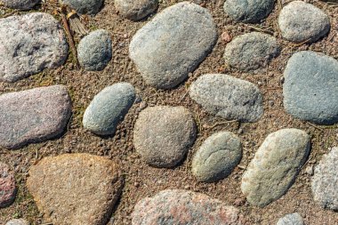 Parke taşlarıyla kaplı bir patika parçası ve aralarında kum olan büyük taşlar. Soyut arkaplan ve dokular olarak kullanılmak üzere.