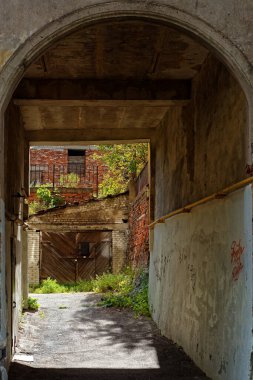 Güneşli bir yaz gününde, Vyborg şehrinde garajı ve tuğlalı evi olan eski bir avluya kemerli bir geçit..