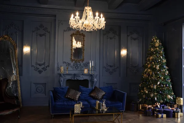 Рождественская елка Темный зал с праздничной атмосферой, уютным камином и диваном. Много подарочных коробок рядом с елкой Стоковое Фото