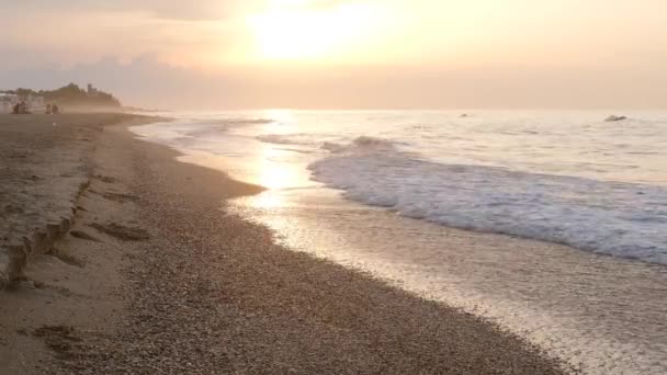 바다 표면에 반사되어 반사되고 잔잔 한 대양의 파도 가 이국적 인 아침해 가 뜨는 모래사장을 강타 한다 — 비디오